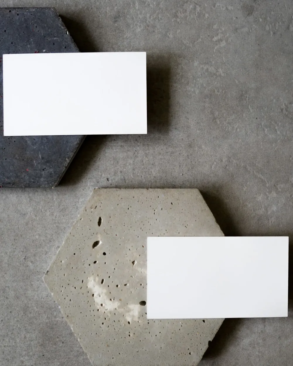 Two blank white business cards resting on hexagonal concrete tiles