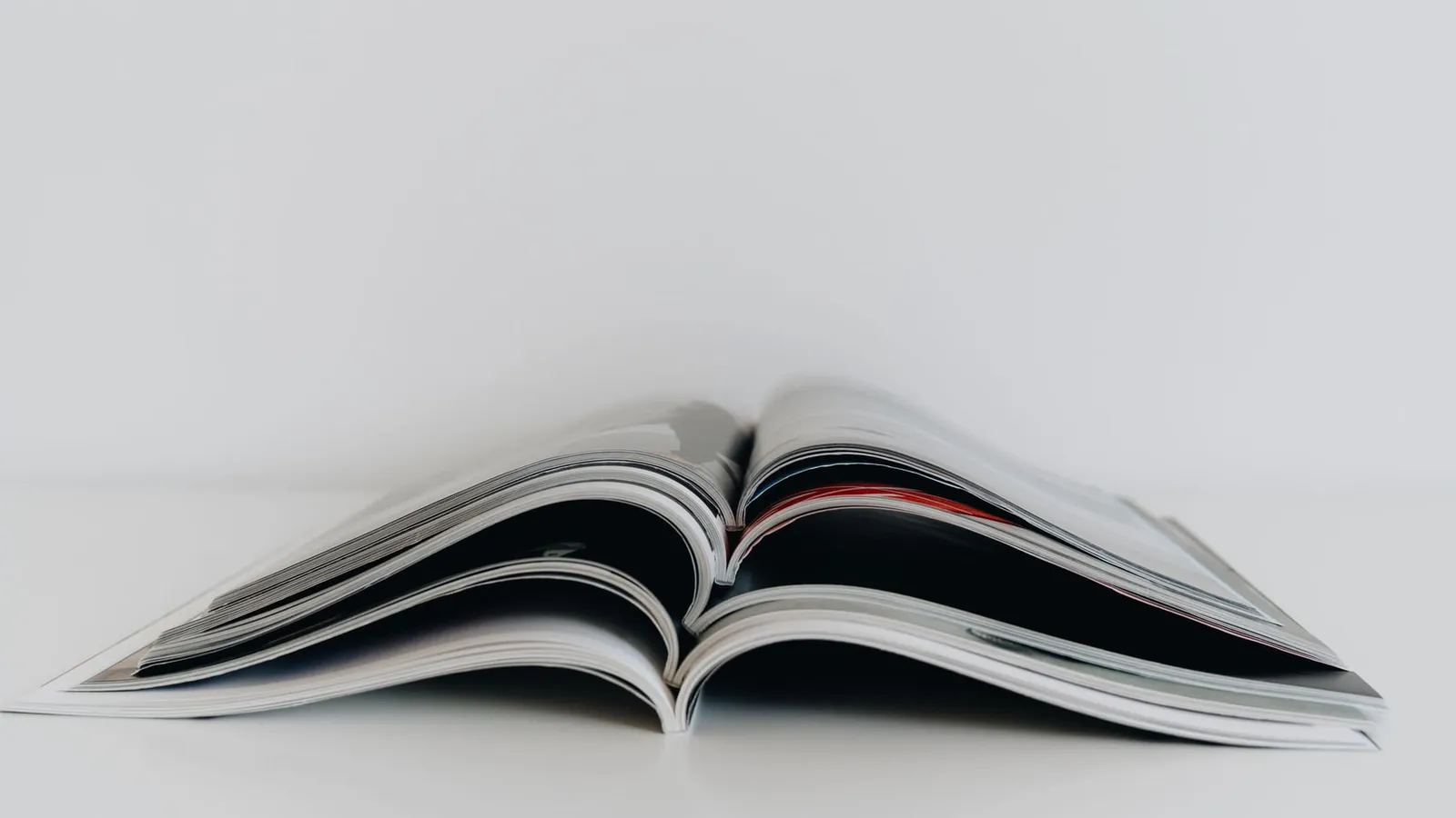 A magazine lying open on a pale surface, its printed pages fanned apart