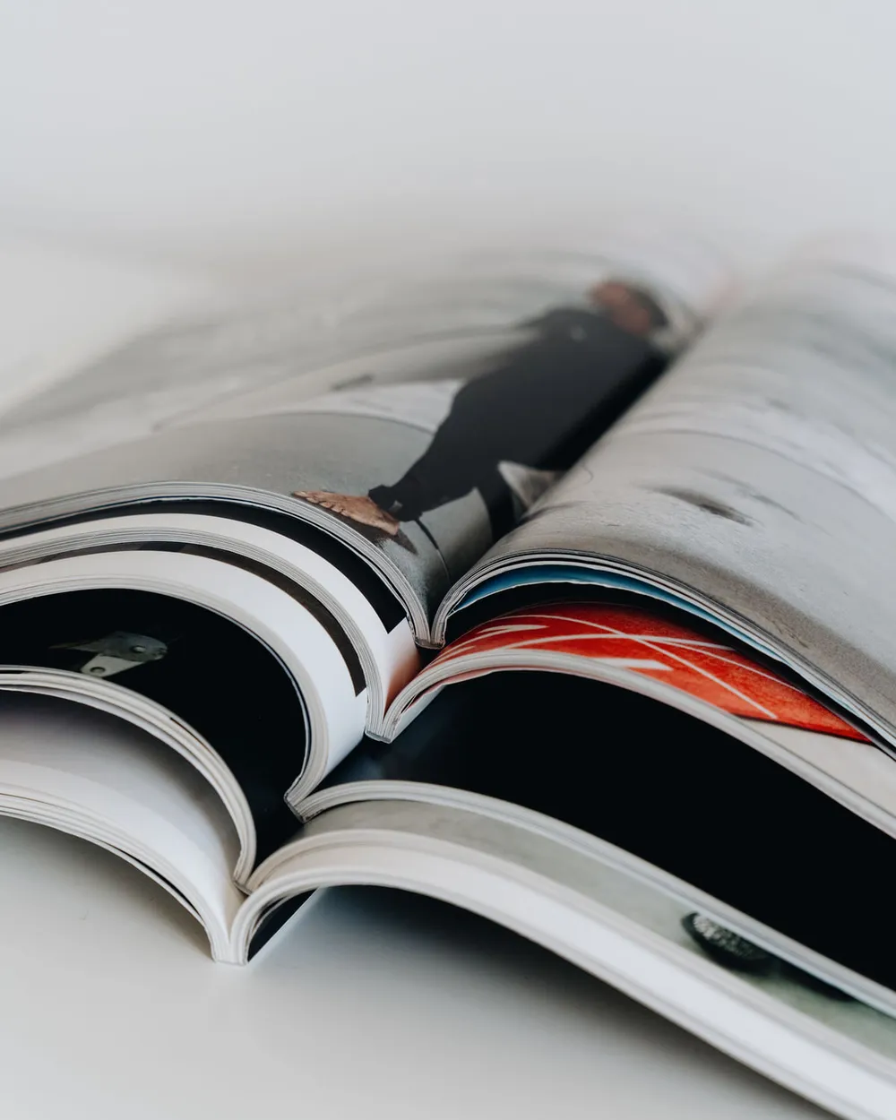 Several magazines lying open in a stack, showing printed page spreads