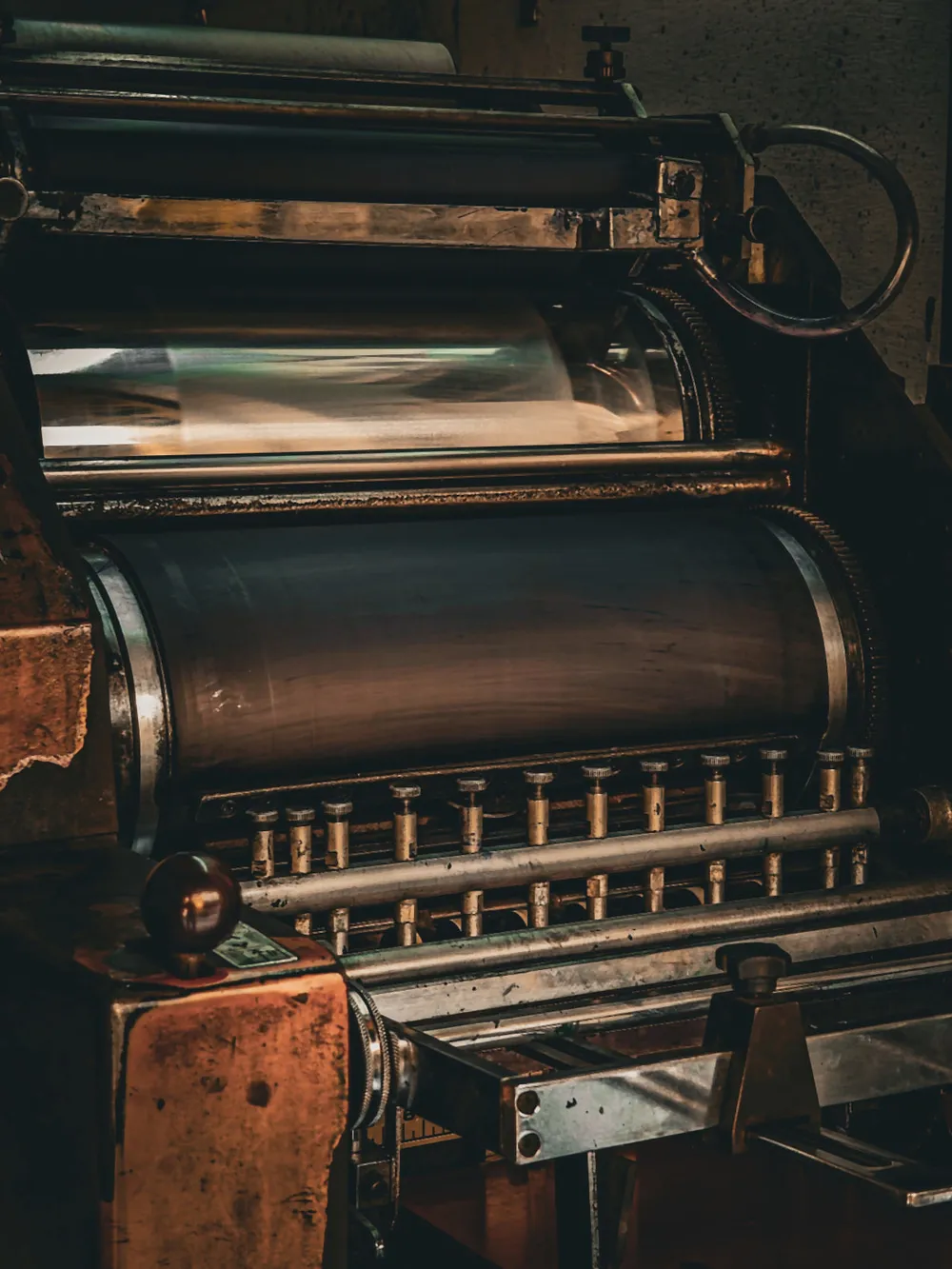 The ink duct of a printing press, with the row of ink keys set along it below the cylinder